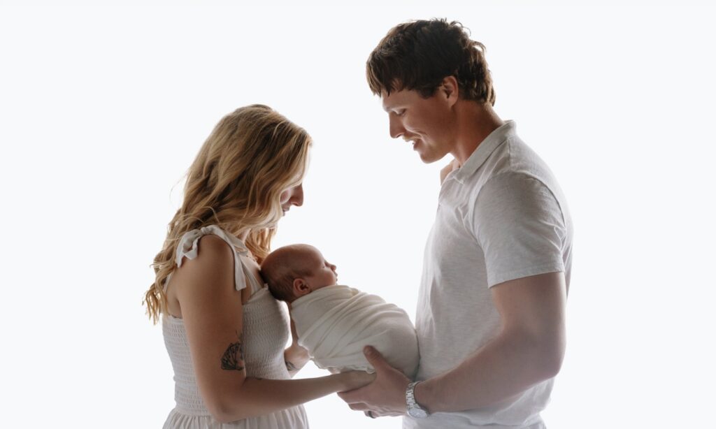 Newborn photographer in Oklahoma City capturing a mother holding her baby in a soft, neutral studio setting
